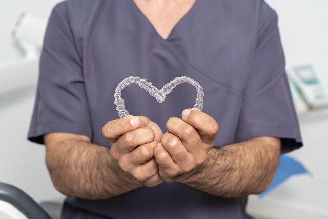 Dentist holding invisalign shaped into a heart